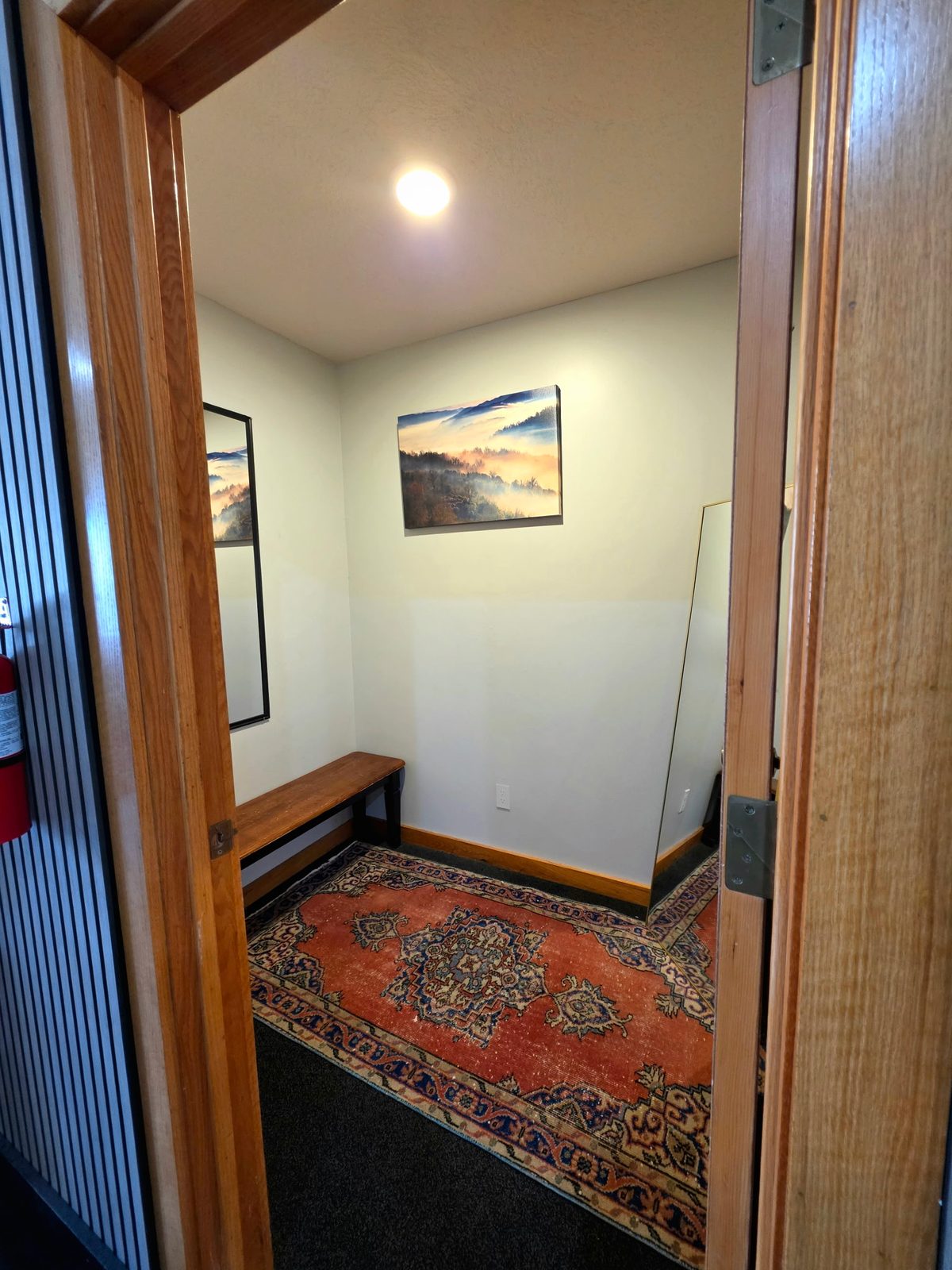 Changing room with a wooden bench, full-length mirrors and a rug